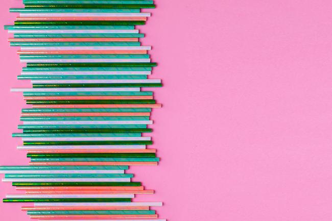 Colorful straws arranged in a pattern on a pink background