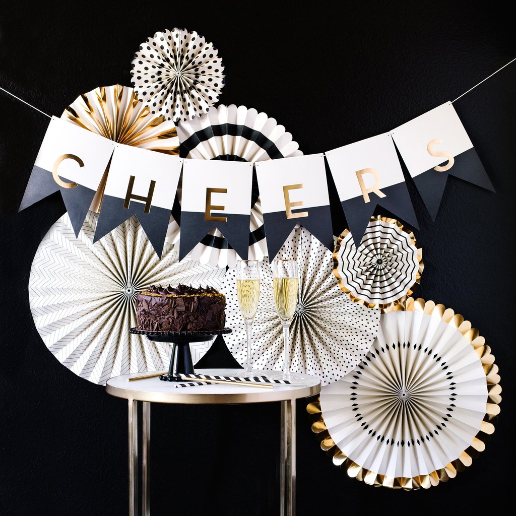 Black, white and gold paper fans and banner that spells out the word Cheers