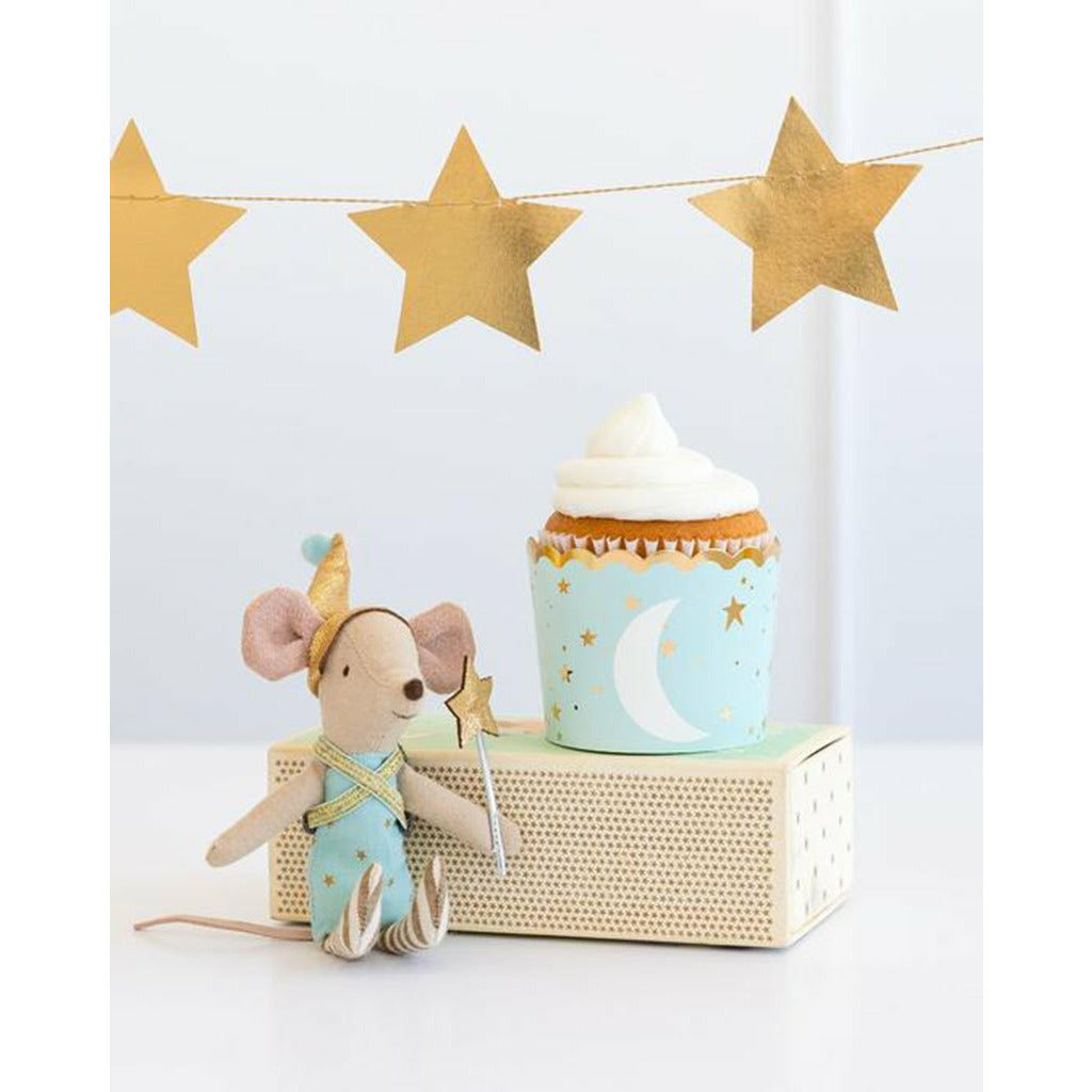 gold star shaped banner above a light blue cupcake cup with printed gold stars and white moon, and a stuffed mouse next to it