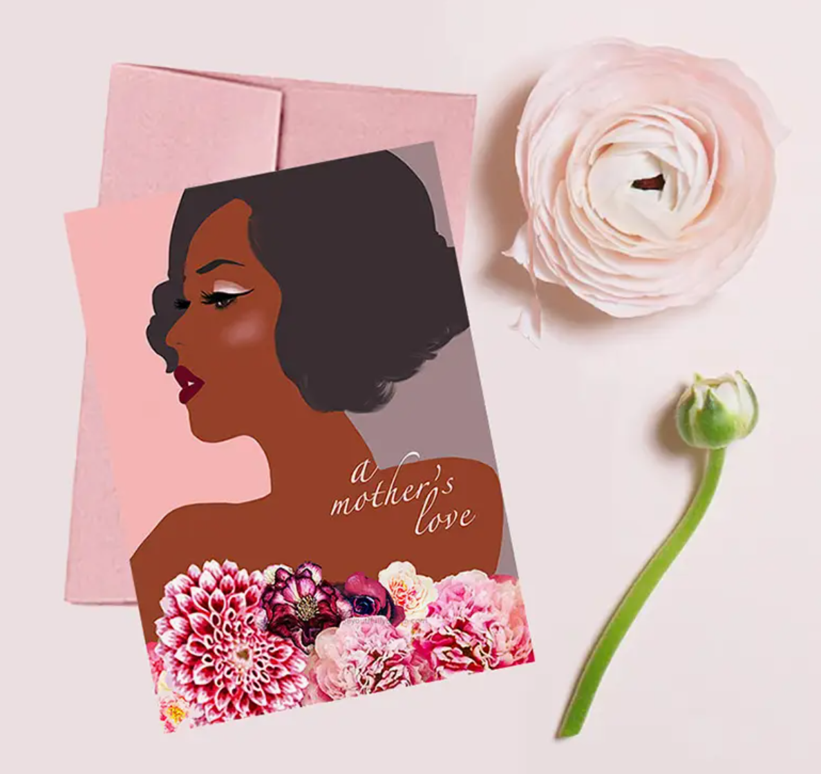 Greeting card with an illustration of a woman from the shoulders up, pink, purple, and cream flowers along with bottom of card like a strapless top, with the title 'A Mother's Love'  lower right side. Pink envelope, flower head, and a green flower stem
