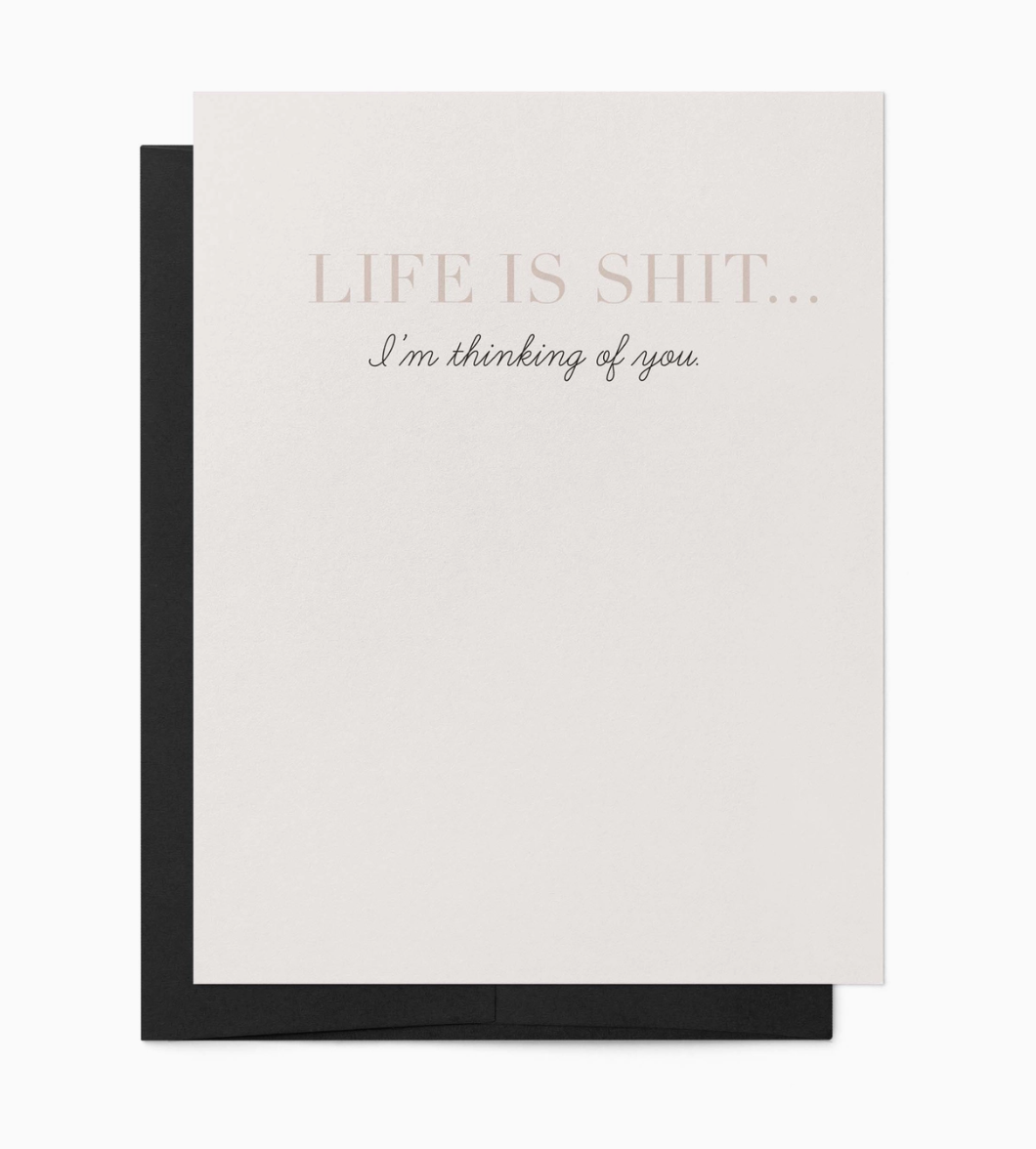 White greeting card with text 'Life is shit... I'm thinking of you' with a black envelope.