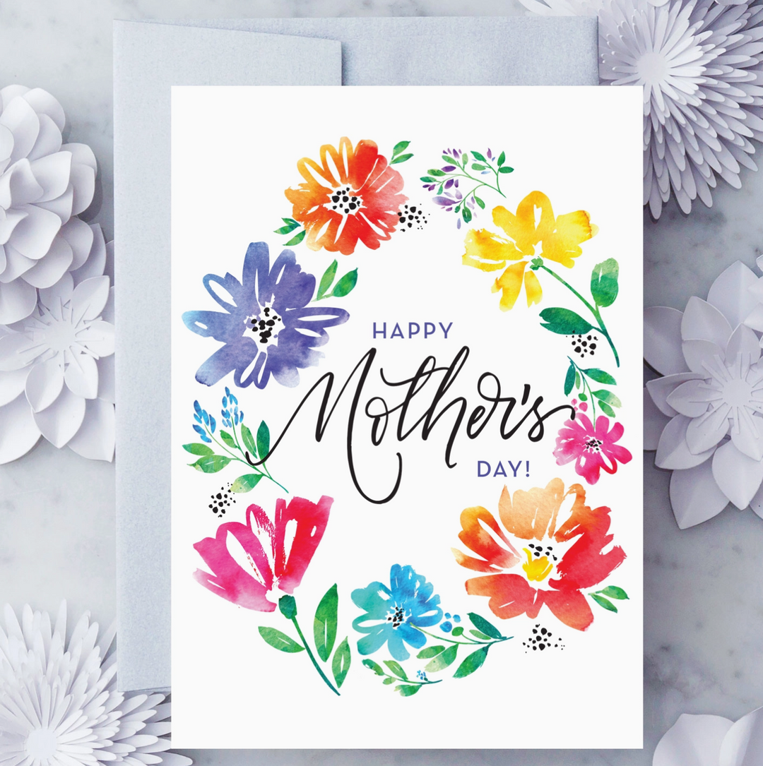 White greeting card with watercolor sketches of flowers creating a wreath around black text that reads "Happy Mother&