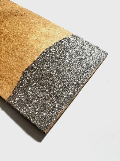 Close up of a kraft paper gift tag with the bottom dipped in gold glitter
