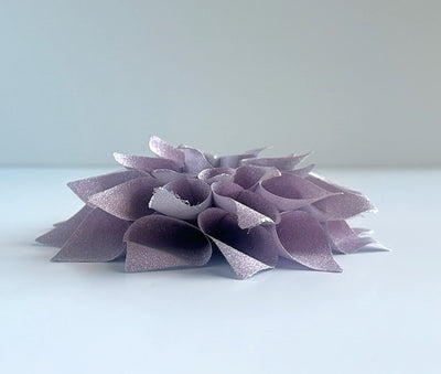 Side view of a glittery lavender and silver colored gift bow