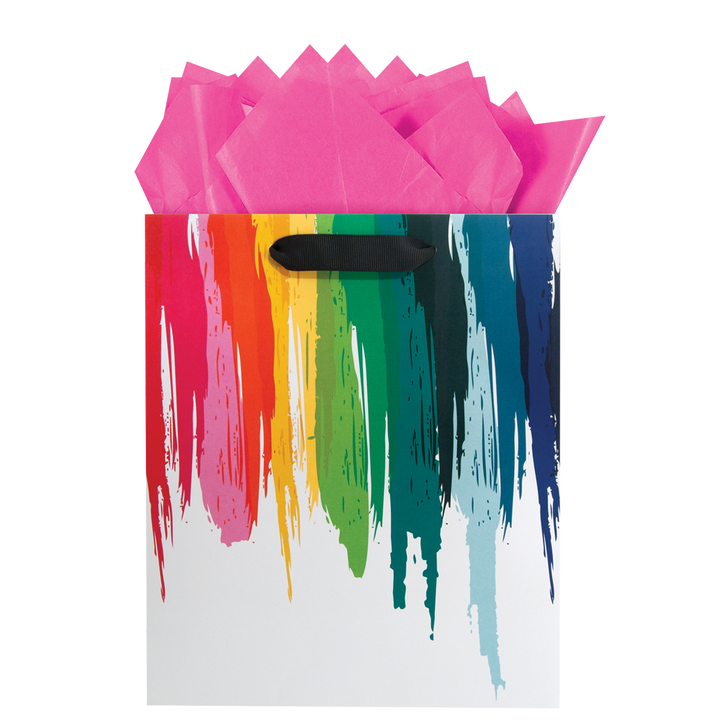 White gloss finish gift bag with a rainbow color paint print appearing to drip from the top to the bottom of the bag with pink tissue paper.