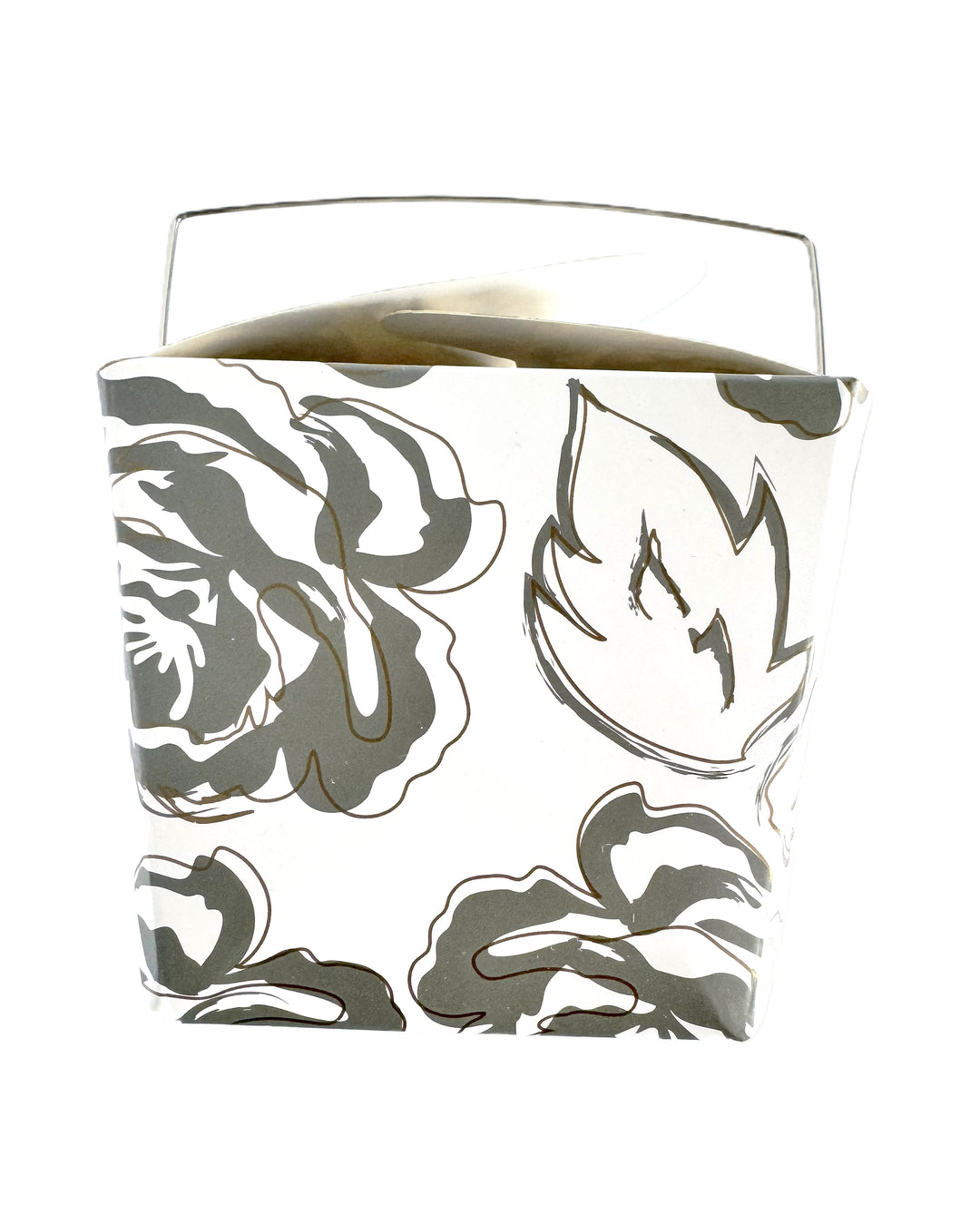 A close-up image of a white take-out style box with an allover silver and gold floral pattern.