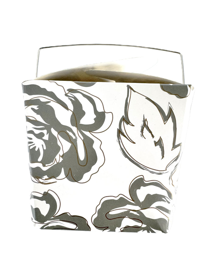 A close-up image of a white take-out style box with an allover silver and gold floral pattern.
