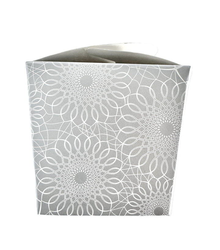 A close-up image of a silver take-out style box with an allover white printed scroll pattern.