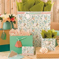set of teal, blush, orange, and green all over floral print patterned gift bags with teal tissue paper and a matching gift tag.