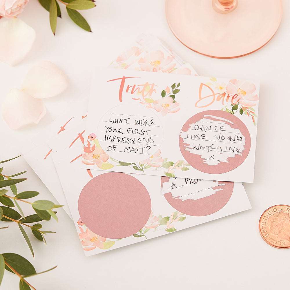 Pack of bridal shower game cards with 'Truth or Dare' written on them, accompanied by scratch-off stickers in a floral design on a pink background