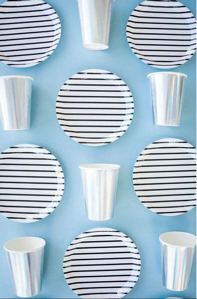 a group of white dessert plate with black printed stripes and silver foil paper cups on a sky blue background