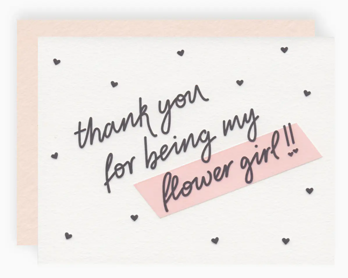 White greeting card with black mini hearts printed allover and text that reads "thank you for being my flower girl!!" paired with a blush pink envelope