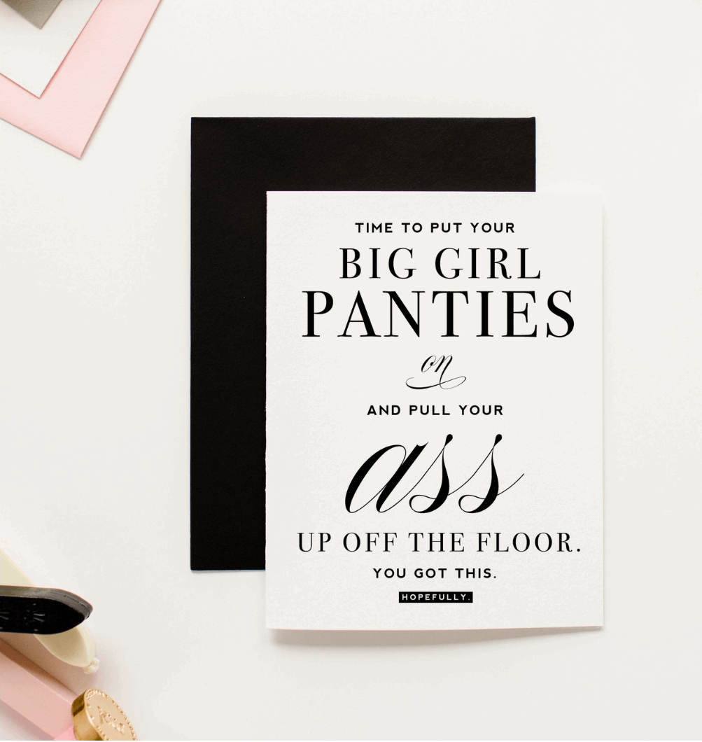 White greeting card with black text that reads "Time to put your big girl panties on and pull your ass up off the floor. You got this. Hopefully." Paired with a black envelope and decorative objects on a pink background