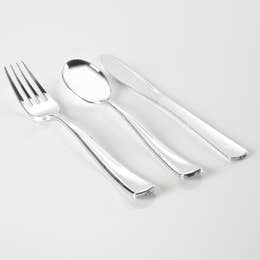 A set of silver plastic cutlery including forks, spoons, and knives laid out on a white surface.