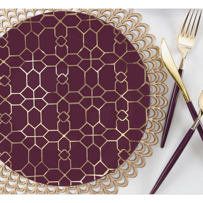 top view of a gold placemat, purple and gold lattice patterned dinner plate and purple handled and gold cutlery set