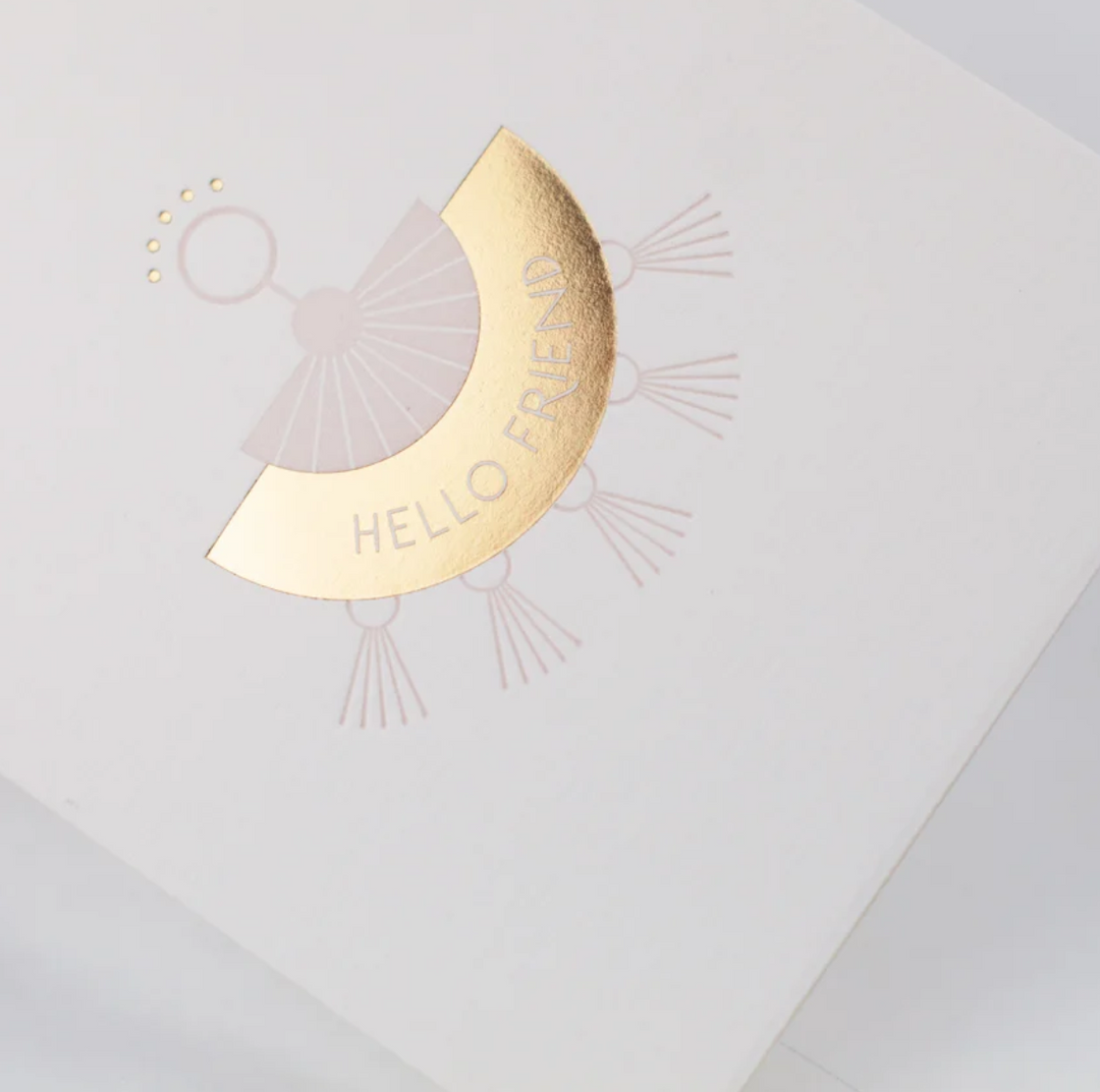 White greeting card, with a pink and gold foil letterpress tassel style earring with the text "Hello Friend"