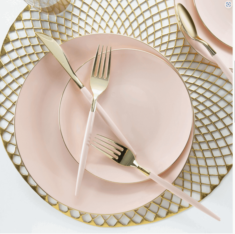 white background with a large gold placemat with a blush pink with gold rim dinner plate topped with a blush pink with gold rim salad plate topped with blush pink handled and gold knife, spoon, and 2 forks.