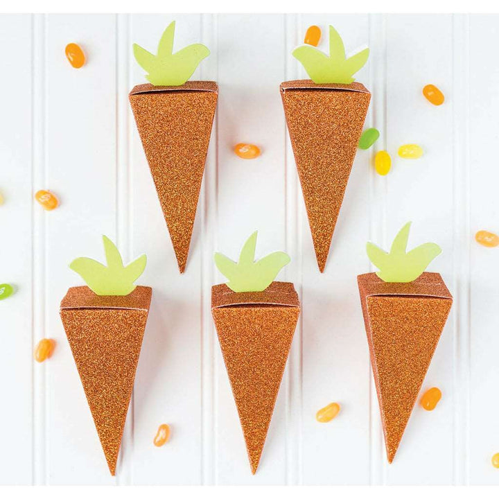 White bead board background, green, yellow, and orange jellybeans scattered around, glittery orange die-cut carrot shaped favor box.