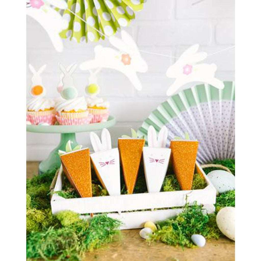 Easter theme setting, carrot and easter bunny favor boxes, moss, easter eggs, cupcakes with easter bunny cake toppers, and an easter bunny banner.