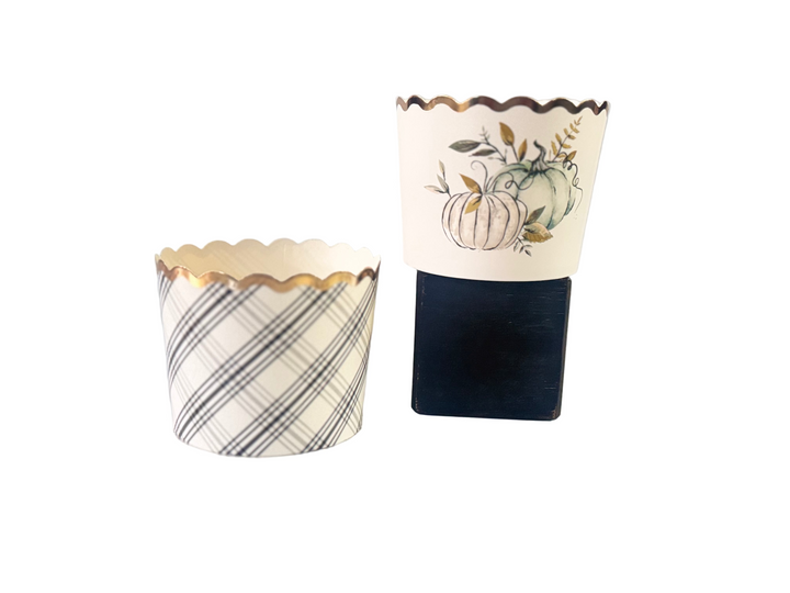 Black and white plaid printed baking cup with gold foil rim and a white gold foil rimmed backing cup with 2 green, black, and gold printed pumpkins and foliage.