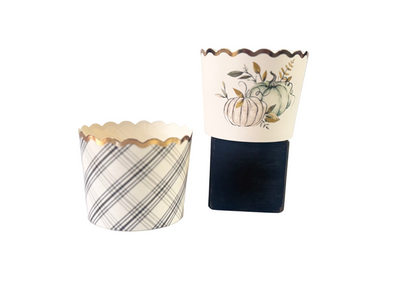 Black and white plaid printed baking cup with gold foil rim and a white gold foil rimmed backing cup with 2 green, black, and gold printed pumpkins and foliage.