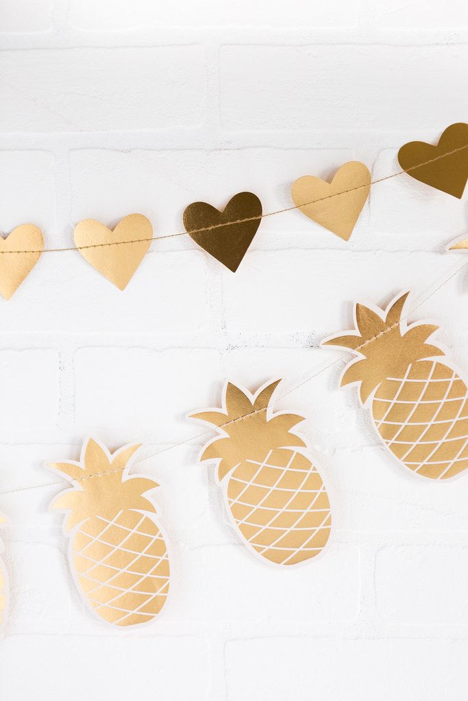 Die cut banner with gold foil pineapples and hearts on a white brick  background