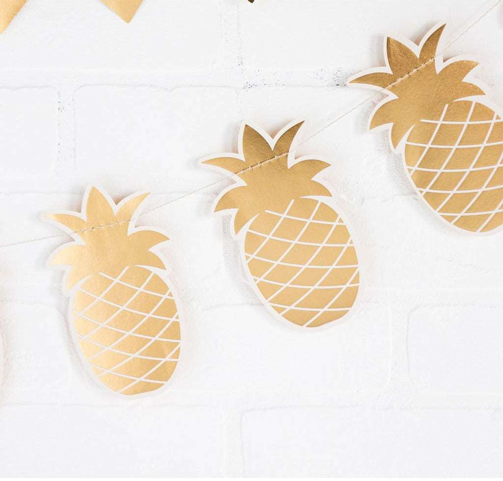 Die Cut Gold Foil Pineapple Banner against a white brick wall