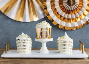 White marble tray with gold handles, 2 white and gold foil dot baking cups, 1 gold foil baking cup with white wreath and the word gather