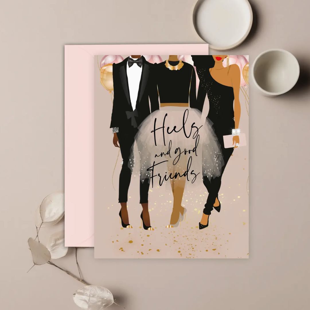A greeting card with an illustration of three stylized women wearing black-tie party outfits and heels. The text on the card reads 'Heels and good friends' with a mauve pink envelope on a neutral background.