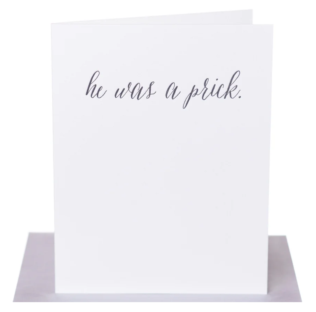 White greeting card with black text "he was a prick." Paired with a metallic silver envelope