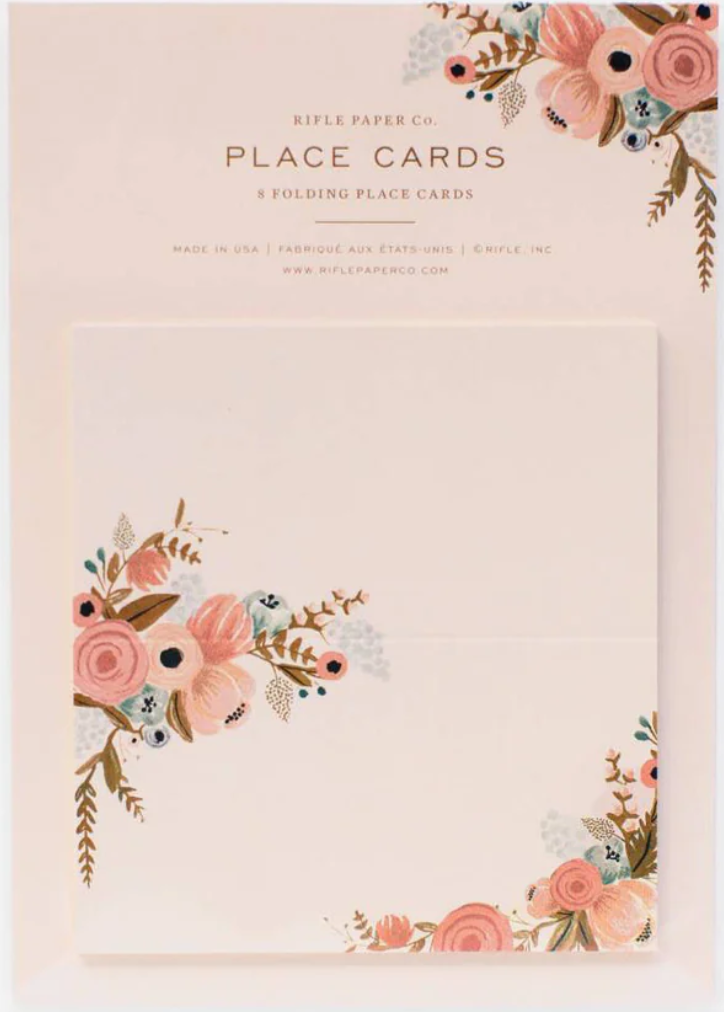 A package of floral print design in the upper left corner and the lower right corner on a beige-peach colored tent fold-style place cards