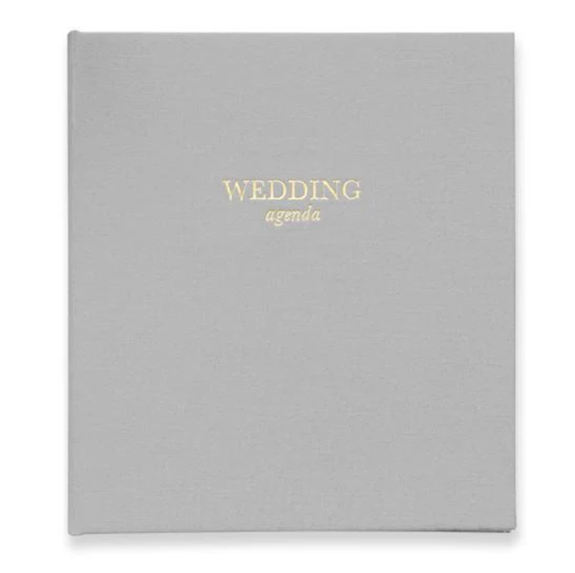 Gray wedding agenda book with gold text that reads wedding agenda on a white background