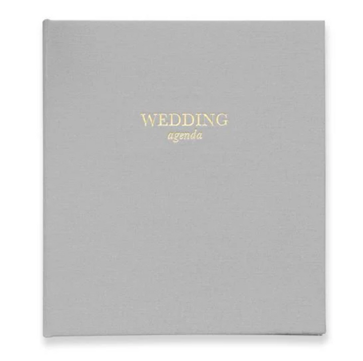 Gray wedding agenda book with gold text that reads wedding agenda on a white background