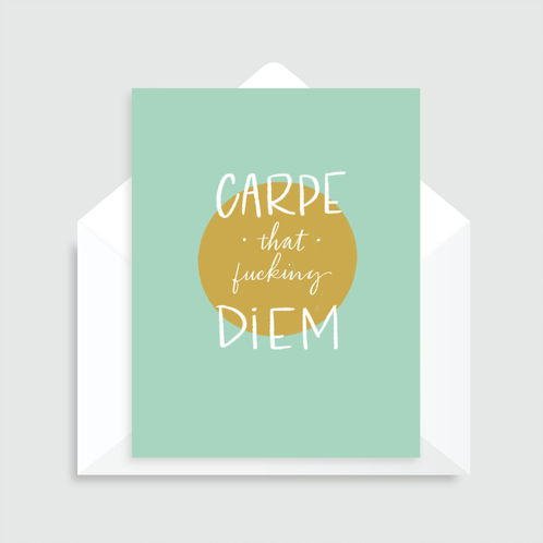 Mint green greeting card with a gold circle and white text that reads "Carpe that fucking diem" over the circle with a white envelope