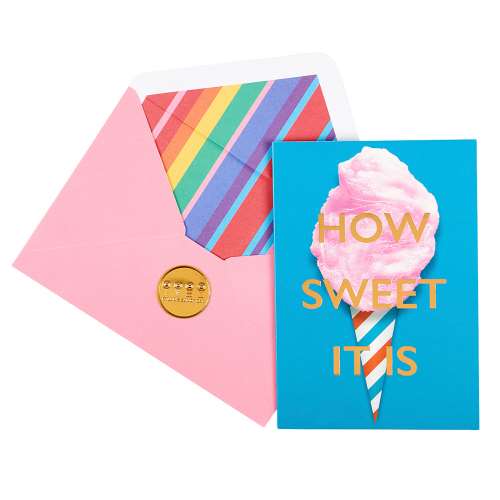 Teal greeting card with an image of cotton candy on a teal, red, and white striped cone, and gold-foil text "ow Sweet It Is" paired with a pink envelope with a rainbow striped liner and a debossed gold seal
