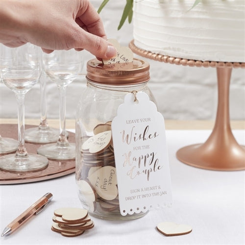 A clear glass mason-style jar with a rose gold lid, labeled &