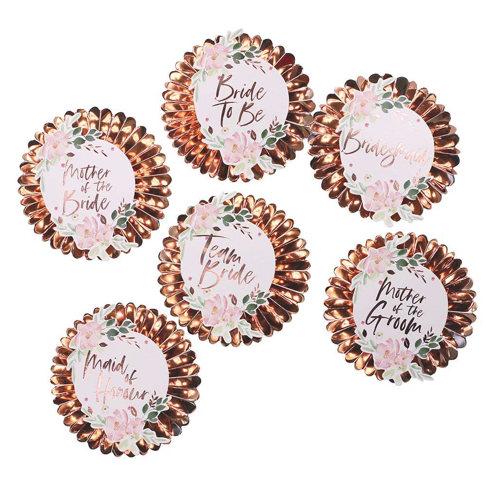 6 flower petal style rose gold pin badges with printed floral stickers in the center. Each center sticker has a word printed on it - mother of bride, bride to be, bridesmaid, team bride, mother of groom, and maid of honor