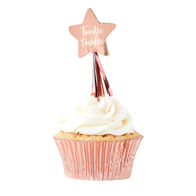 Rose gold foil, star-shaped cupcake toppers with tassels and phrase “Twinkle Twinkle” in script on the star placed on top of a cupcake.