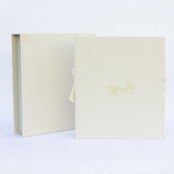 A beige fabric-covered wedding planner book set on a white background