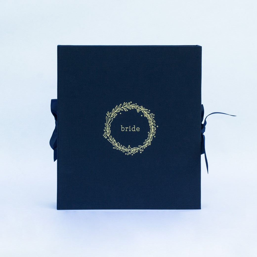 A navy fabric-covered wedding planner book on a white background-