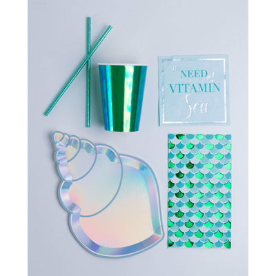Seashell shaped light blue iridescent paper plate, emerald-green iridescent paper cup with matching paper straw, light blue paper cocktail size napkin with statement "In need of vitamin sea" printed in silver and turquoise, foil printed fish scale patterned dinner napkin size in turquoise, emerald-green, and light blue