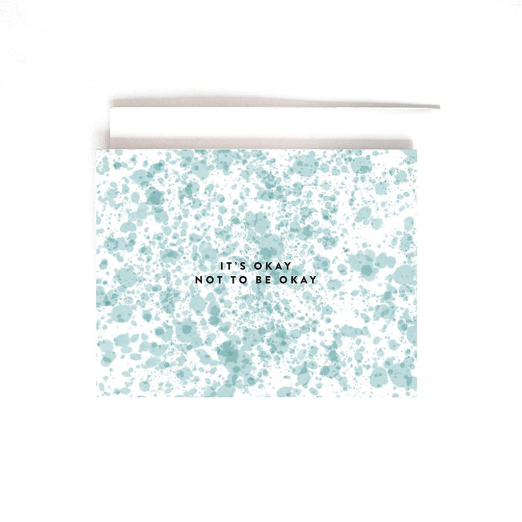 White greeting card with allover blue-green splatter print with black text that reads "it&