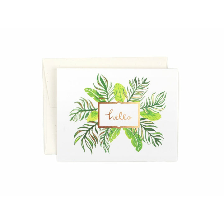 White greeting card with gold foil outlined square with the text "hello" in gold foil and illustrated green and gold palm and fern leaf green design coming out from behind the square from all sides, and a white envelope