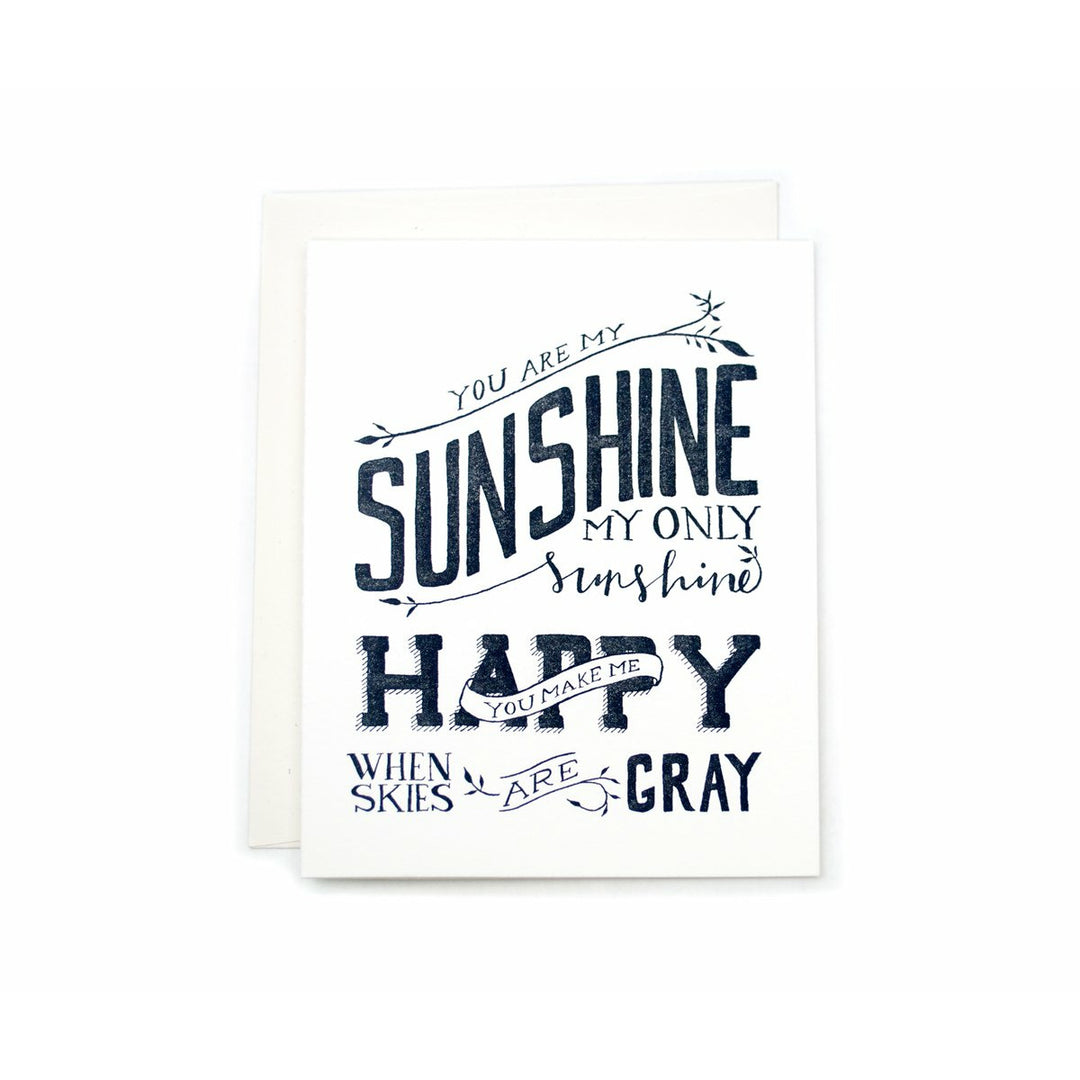 White greeting card with text that reads "You Are My Sunshine, my only sunshine, you make me happy, when skies are gray" in various font styles with a white envelope