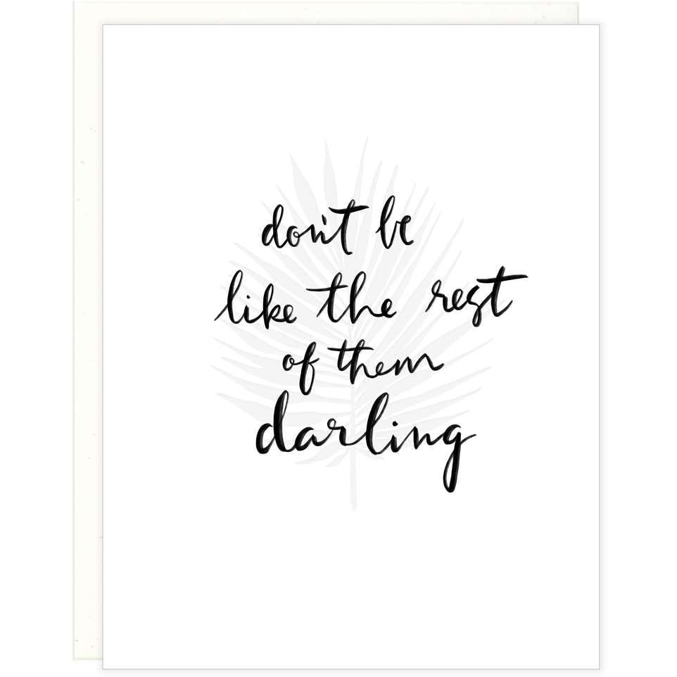 White greeting card with black text that reads "don't be like the rest of them darling" on top of a letterpress fern stem with a white envelope