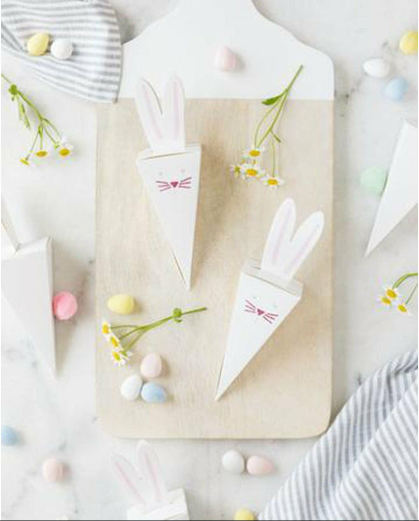 white marble table with white and grey tea cloths, daisy flowers, pastel color candy, and easter bunny die cut favor boxes.