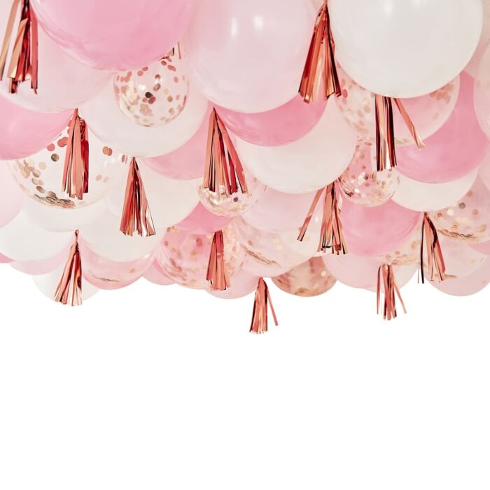 A decorative balloon ceiling arrangement featuring rose gold, pink, and white balloons with metallic rose gold tassels.
