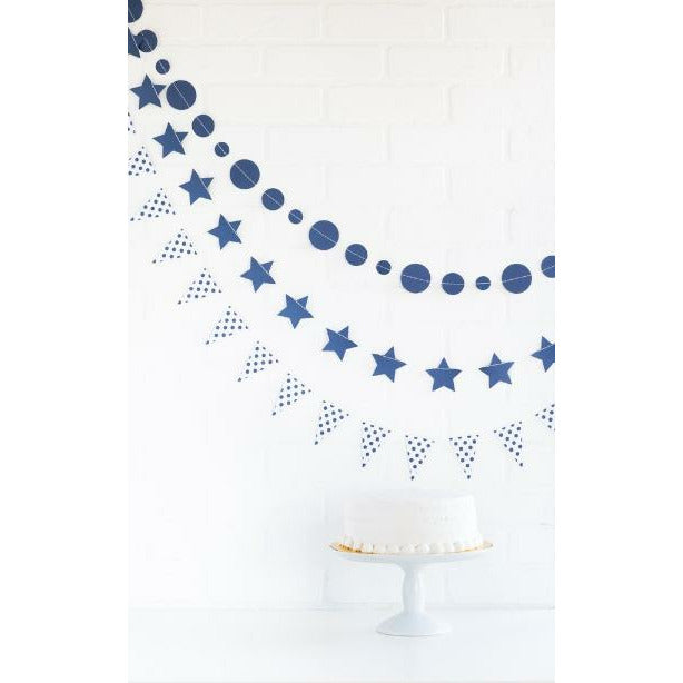 3-piece die cut banner, 1 with navy colored circles, 1 with navy colored stars, and 1 with white with navy colored polka dot pennant style above a cake on a white cake stand