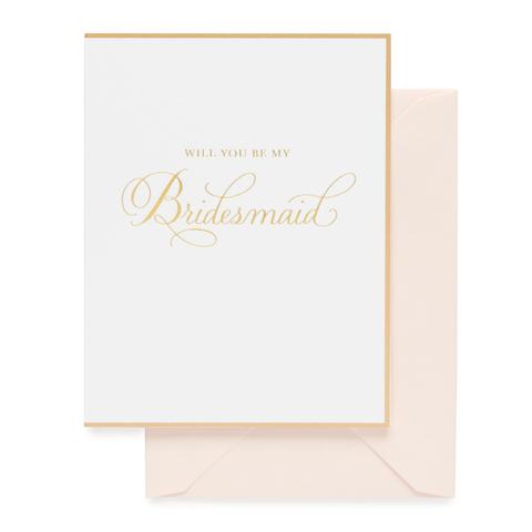 A white greeting card with gold foil "Will You Be my bridesmaid" text and border. Paired with a blush pink envelope.