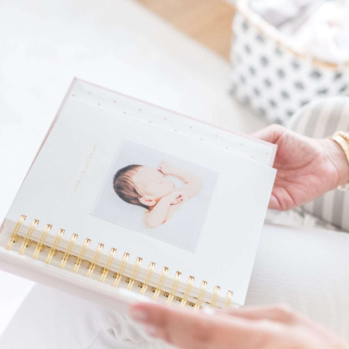 hands holding a baby book with a picture of a newborn baby in it.